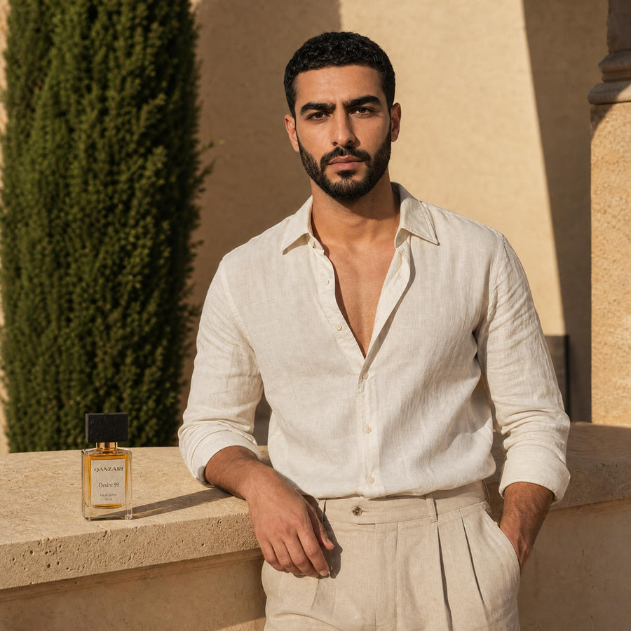 A man in linen beside the Qanzari Desire 99 50ml bottle in warm evening light