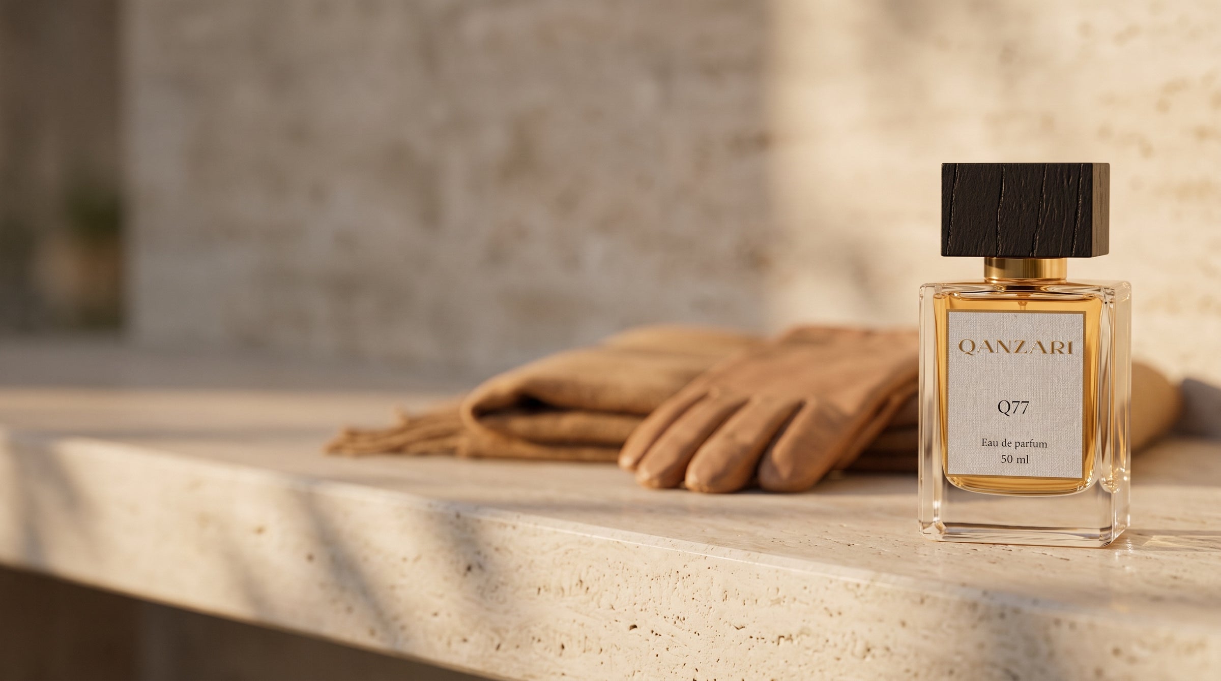Qanzari Q77 eau de parfum on travertine with camel leather gloves in warm late-autumn light